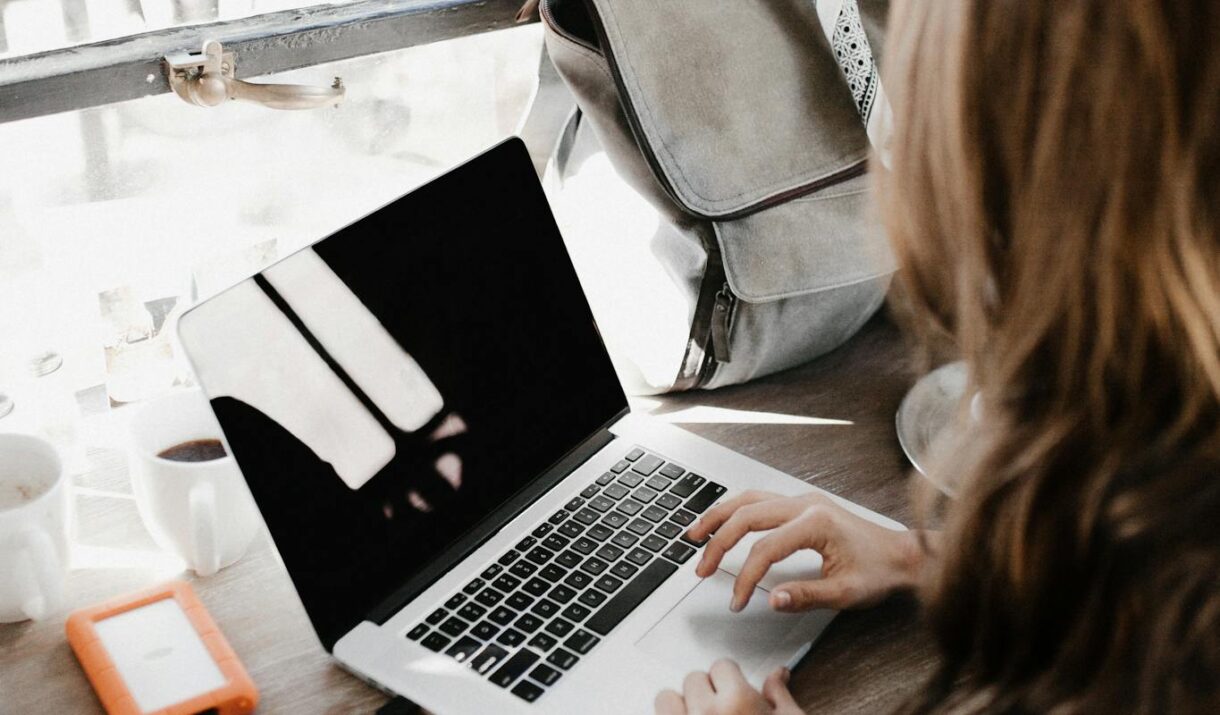 Close-up Photography of Woman Sitting Beside Table While Using Macbook