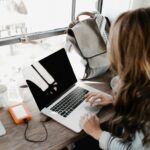 Close-up Photography of Woman Sitting Beside Table While Using Macbook