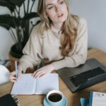 Focused businesswoman writing in notebook near laptop